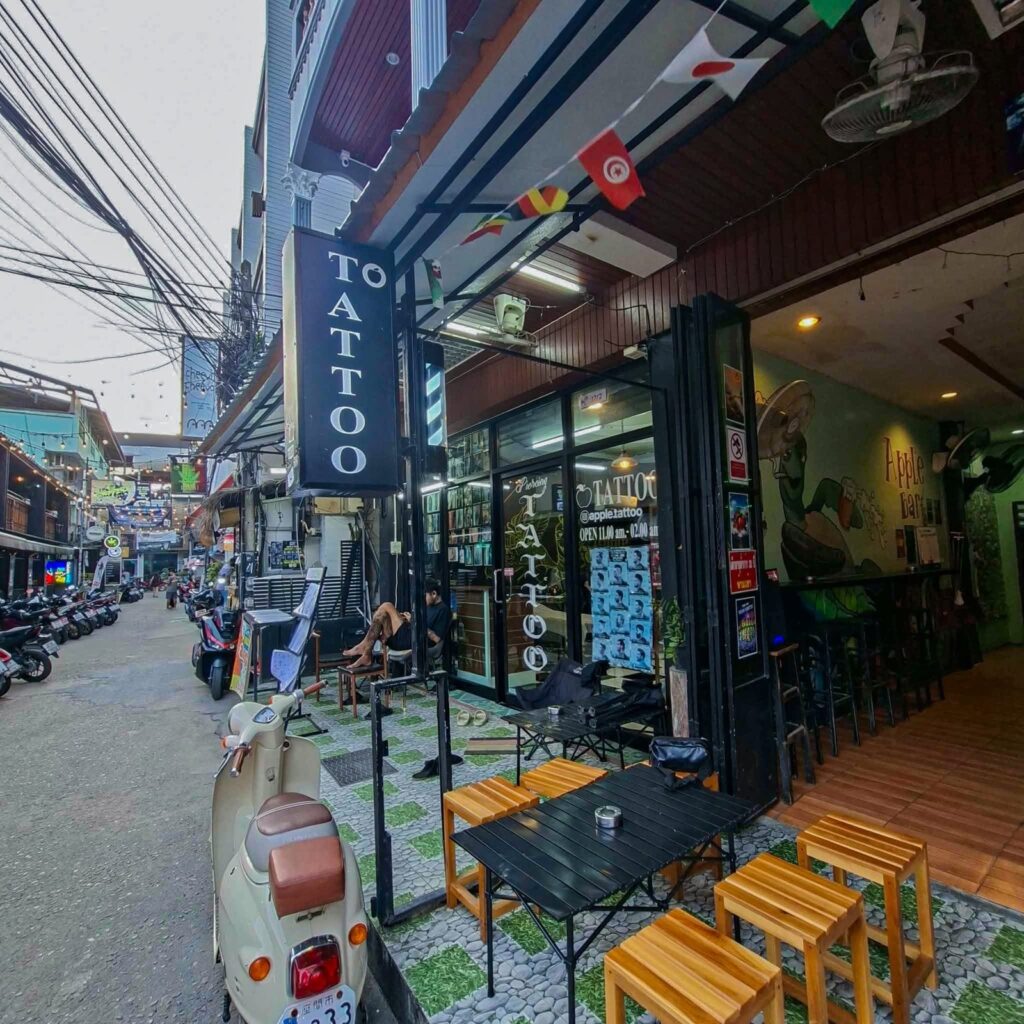 Street-level entrance showing Apple Bar and the neighbouring tattoo shop signage.