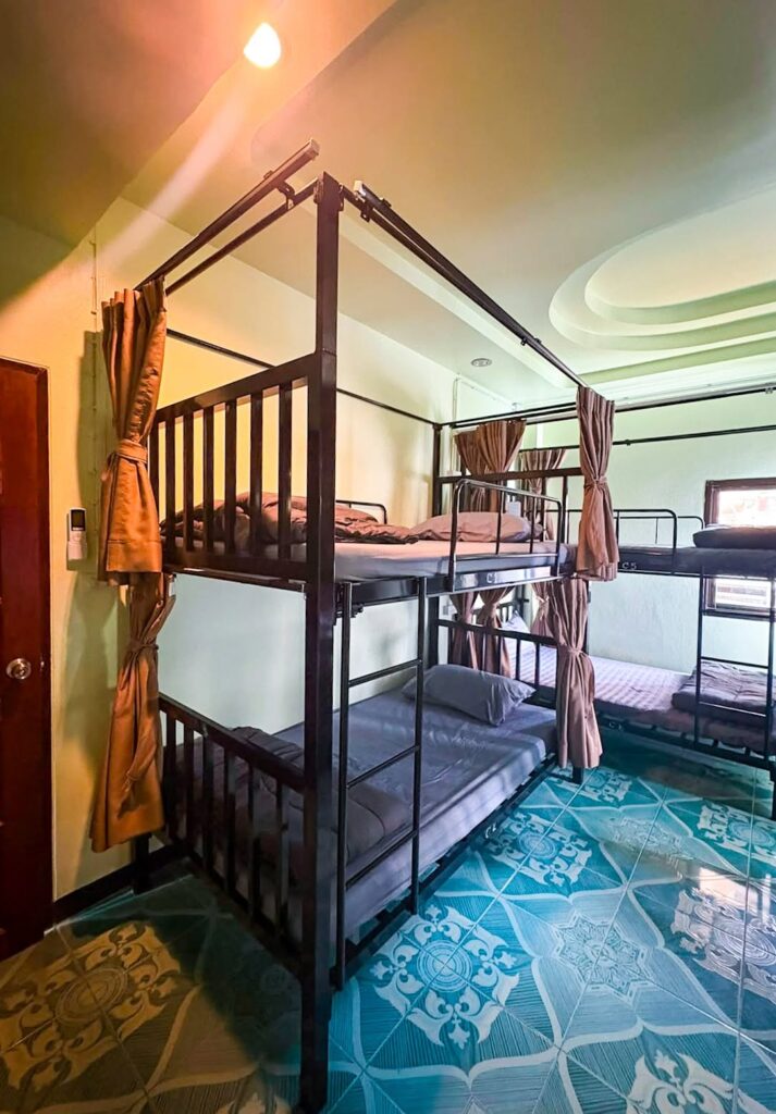 Dorm room with metal bunk beds and tiled floor at Apple House Hostel.